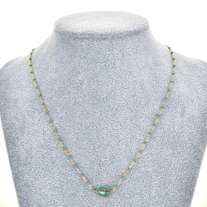 Détail d'un collier doré avec perles bleues et pendentif ovale oeil et main de Fatma