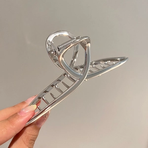 Macro shot of a large silver metal shark hair claw clip with a glossy polished finish