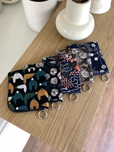 Set of five mini linen coin purses with fine floral embroidery and metal rings on a wooden desk