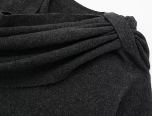 Close-up of asymmetrical shoulder pleats and tie detail on charcoal gray knit outerwear