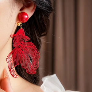 Gros plan d'un clip d'oreille poisson koi rouge en métal porté par un mannequin de mode