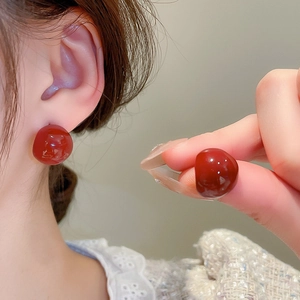 Gros plan sur d'élégantes boucles d'oreilles rondes rouges avec une finition miroir polie