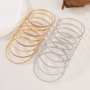 Detail shot of ten-piece gold and silver stackable bracelets on textured linen cloth