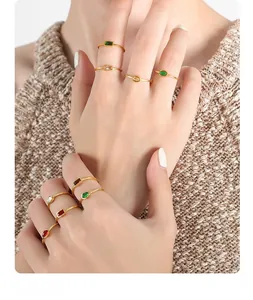 Close-up of stacked thin gold rings with emerald and ruby crystals on model fingers