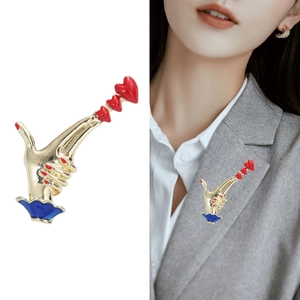 Creative hand-shaped heart brooch in gold metal shown on white background and grey suit lapel