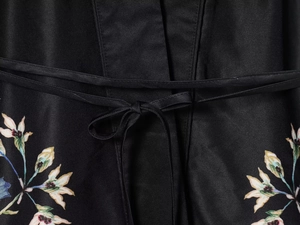 Detail of black floral wrap blazer with fabric waist tie and botanical print patterns
