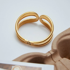 Detail of gold-plated stainless steel cuff with hollow dual-line design and spring hinge