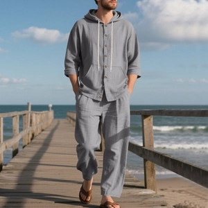 Detail of grey linen shirt with hoodie and drawstring pants on seaside wooden bridge