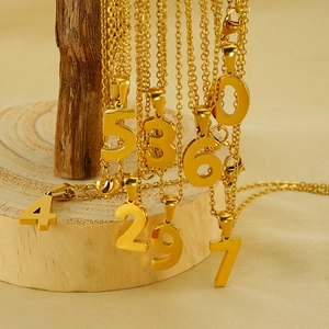 Artistic display of 18K gold-plated stainless steel number necklaces on a wooden branch