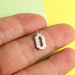Punk style stainless steel razor blade pendant charm held between fingers for DIY jewelry