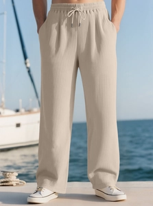 Detail of men's beige casual trousers with vertical pleated texture and drawstring waist