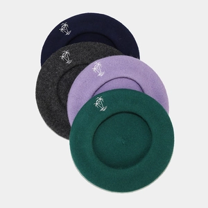 Detail of wool beret hats with palm tree embroidery in navy, grey, purple and green