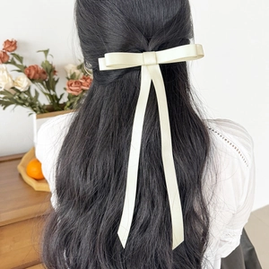 Elegant cream white long ribbon bow hair clip shown on a model for a sweet aesthetic look