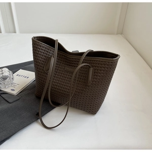 Detail shot of the deep brown woven tote bag texture and slender shoulder straps