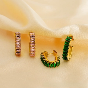 Detail of U-shape gold earrings with baguette-cut pink and emerald green zircons