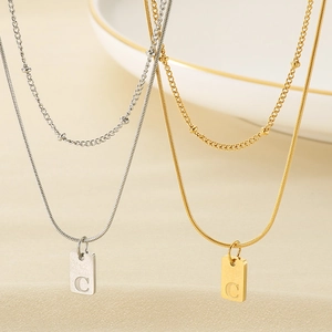 Detailansicht der doppelten Schlangenkette in Gold und Silber mit C-Buchstabenanhänger
