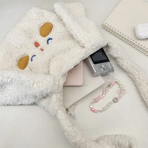 Dettaglio della simpatica borsa a tracolla in peluche bianca con ricamo e accessori vari