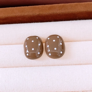 Detail of brown resin oval stud earrings with white polka dots on a velvet display