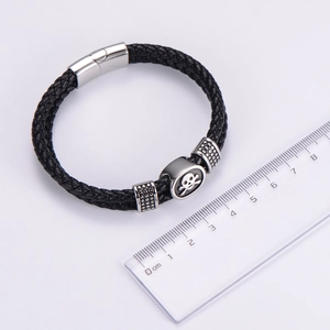 Detail of black braided leather bracelet with skull slider and magnetic clasp