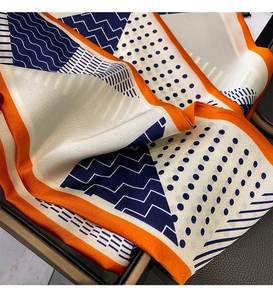 Detailed close-up of patterned silk scarf with orange edges and blue geometric polka dots