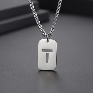 Détail du pendentif rectangle argenté avec lettre T évidée sur chaîne texturée