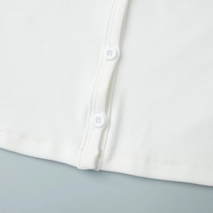 Close-up of white ribbed knit fabric showing neat stitching and matching buttons