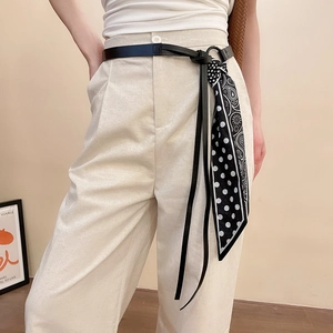 Détail d'une ceinture en cuir noir avec foulard à pois noir et blanc et pompon paisley chic