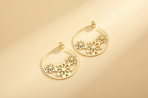 Detailed close-up of gold hollow petal decorations on large stainless steel hoop earrings
