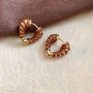 Vue macro de boucles d'oreilles cœur en or 18k avec cuir marron sur tissu doux