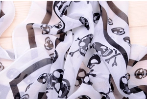 Detailed close-up of white chiffon fabric with black pirate skull and crossbones print