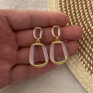 Close-up of gold geometric drop earrings with lavender marble enamel held in hand