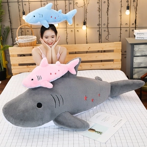 Three plush shark toys in grey, pink and blue with star embroidery on home bedding