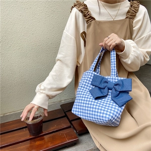 Blue and white plaid handbag featuring a large bow on a minimalist textured background