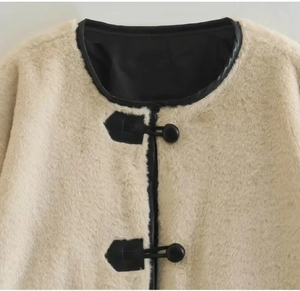 Détail d'une veste beige en fausse fourrure montrant les boutons noirs et la texture douce