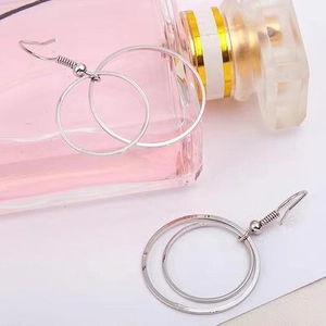 Minimalist double layered silver hoop earrings displayed on white background with perfume bottle