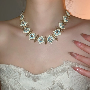 Detail view of vintage diamond-set heart necklace with white and blue enamel patterns