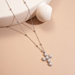 Detail of silver cross pendant with white pearls and sparkling zircons on a station chain