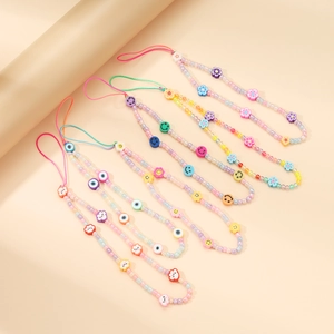 Detail of four colorful handmade beaded phone lanyards with smiley and flower patterns