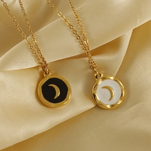 Detailed view of 18K gold plated steel moon necklaces on beige silk fabric