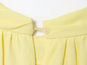 Macro-opname van de achterkant van de lichtgele chiffon blouse met knoopsluiting