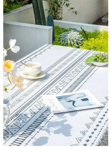 Detail of bohemian cotton linen tablecloth with black geometric patterns in sunny garden
