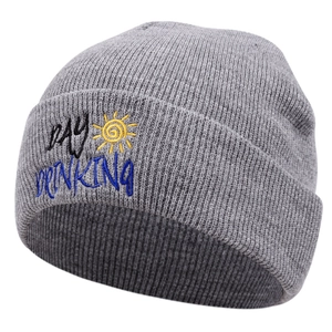 Close-up of grey knit beanie featuring DAY DRINKING embroidery and yellow sun icon