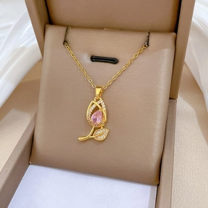 Detailed close-up of a golden tulip necklace with a pink stone in a jewelry box