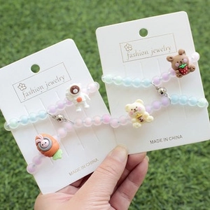 Gros plan de bracelets en perles macaron colorées avec cœurs aimantés sur pelouse
