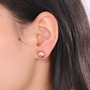 Polished rose gold stainless steel hemisphere stud earrings shown on a female ear model