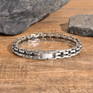 Detail of silver and black stainless steel link bracelet with folding clasp on wood