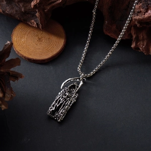 Vue détaillée du pendentif faucheuse en argent sur un fond en bois sombre rustique