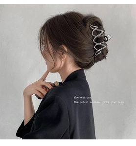 Detail of silver wavy metal hair claw clip holding a low bun for a modern French style