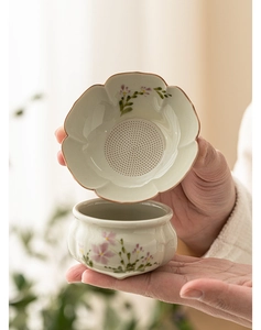 Close-up of ceramic tea strainer with hand-painted pink daisies and fine filter holes