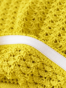 Detail shot of lime green textured knit fabric with white satin ribbon trim detail